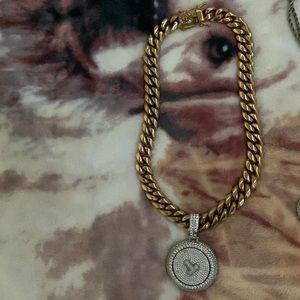 A Cuban link with a big pendant that spins and has the letter T